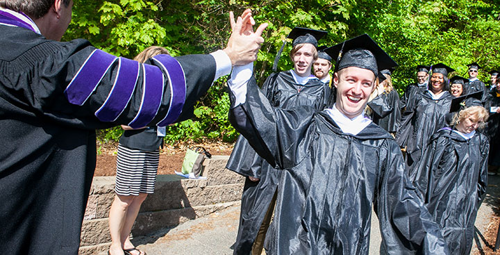 A 鶹Ƶ graduate receives a high five from the College's President on Commencement Day